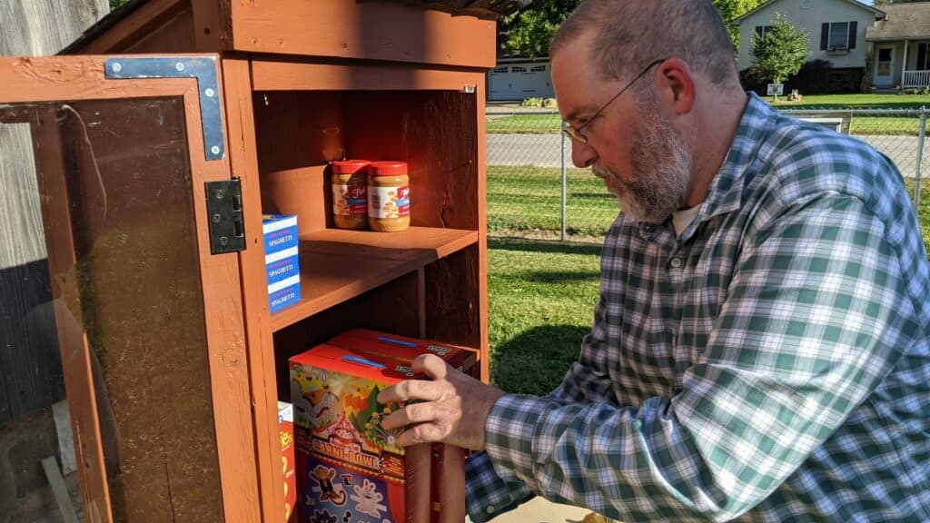 Photo of a man stocking a community food box