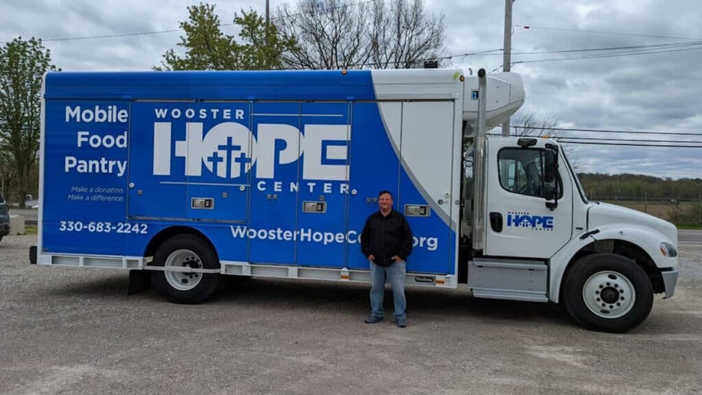 Photo of Wooster Hope Center's mobile food pantry with a man standing in front of it.